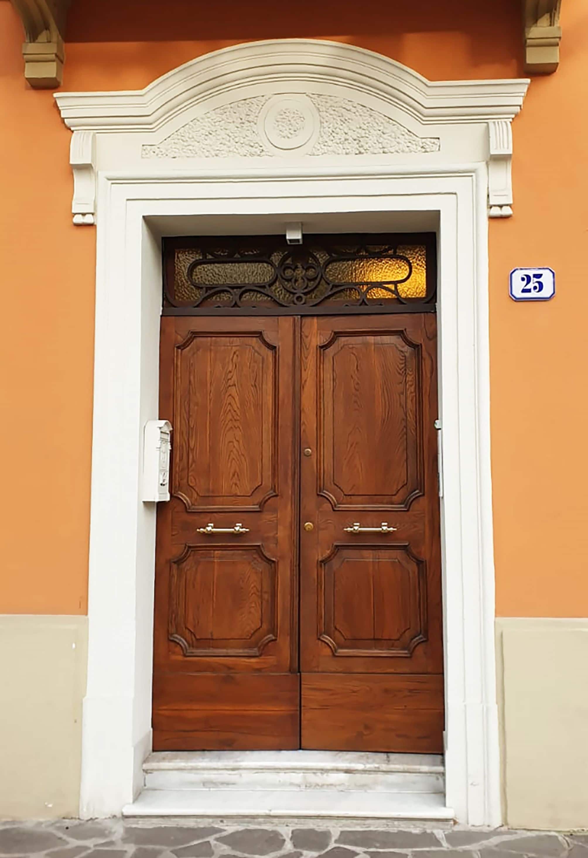 A double wooden door with a white frame and a decorative arch above it.