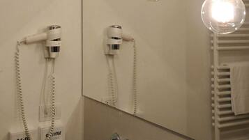 Un baño con un espejo grande, un lavabo y dos secadores de pelo montados en la pared.