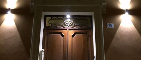 A wooden door with a decorative glass panel and a balcony with lights.
