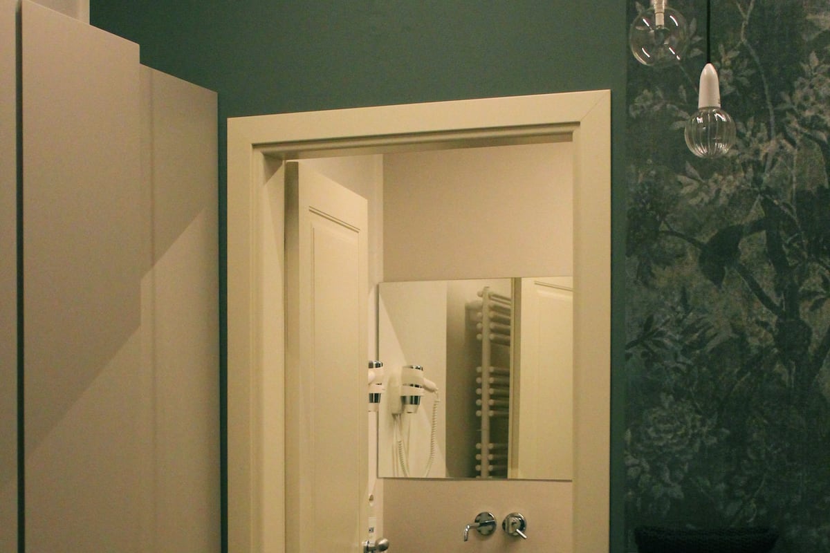 A bathroom with a white door, a sink, a mirror, and a towel rack.