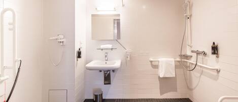A modern bathroom with a white sink, mirror, and shower.