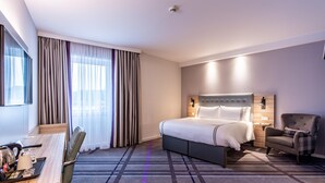 A hotel room with a bed, a desk, a chair, a TV, and a window with curtains. - Premier Inn Hannover City University (Hannover)