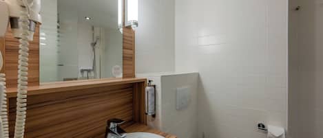 Een badkamer met een houten wastafelmeubel, een witte wastafel, een spiegel en een douche.