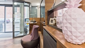 A reception area with a modern design, featuring a wooden reception desk, a large pineapple sculpture, and a seating area with a purple chair. - elaya hotel munich city,  Trademark Collection by Wyndham (Munich)