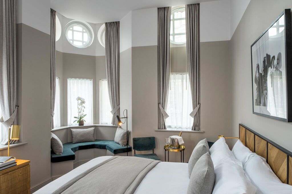 A hotel room with a bed, seating area, and large windows.