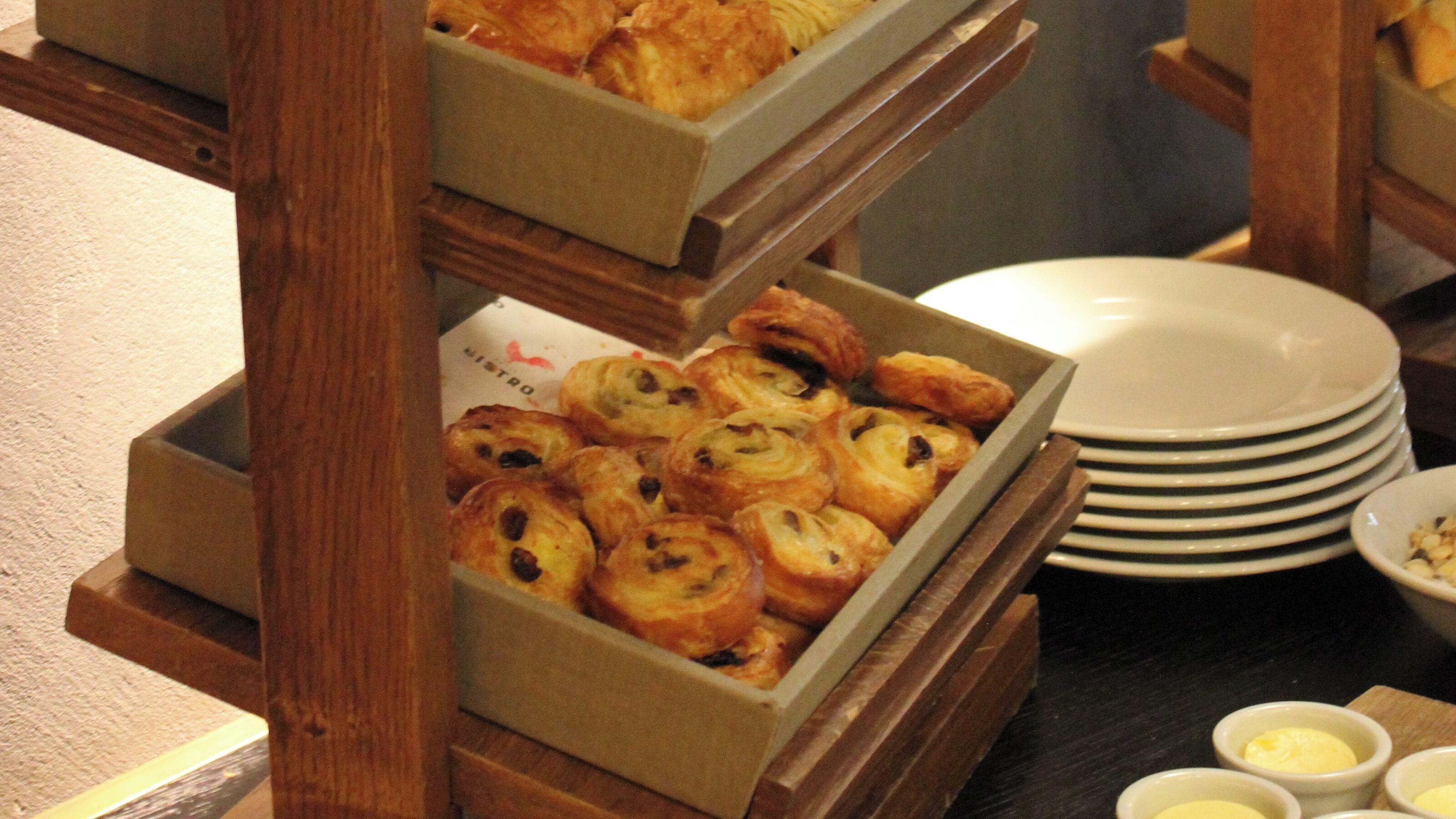 A buffet setup with pastries and small bowls of butter.