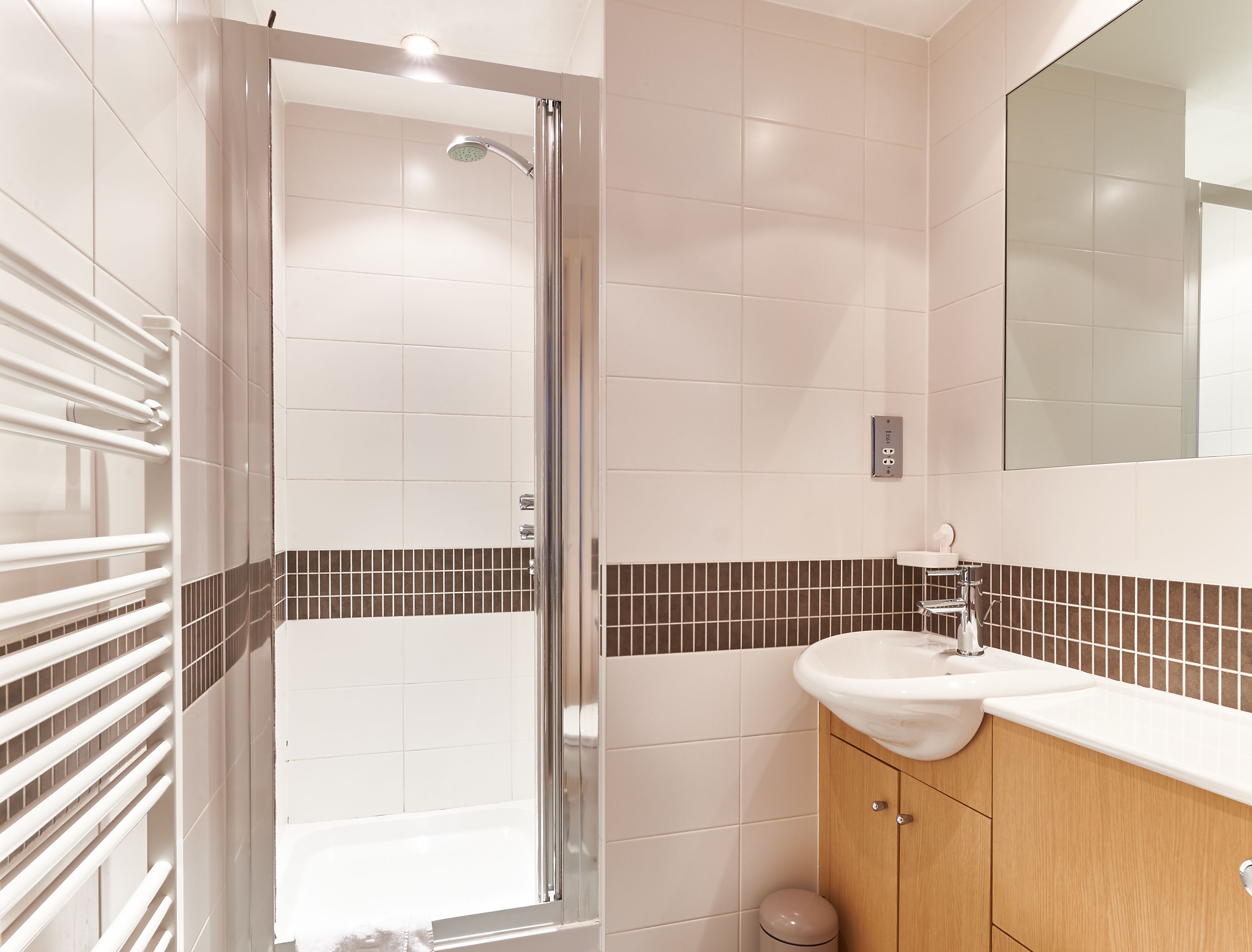 A modern bathroom with a glass-enclosed shower, a white sink, and a wooden cabinet.