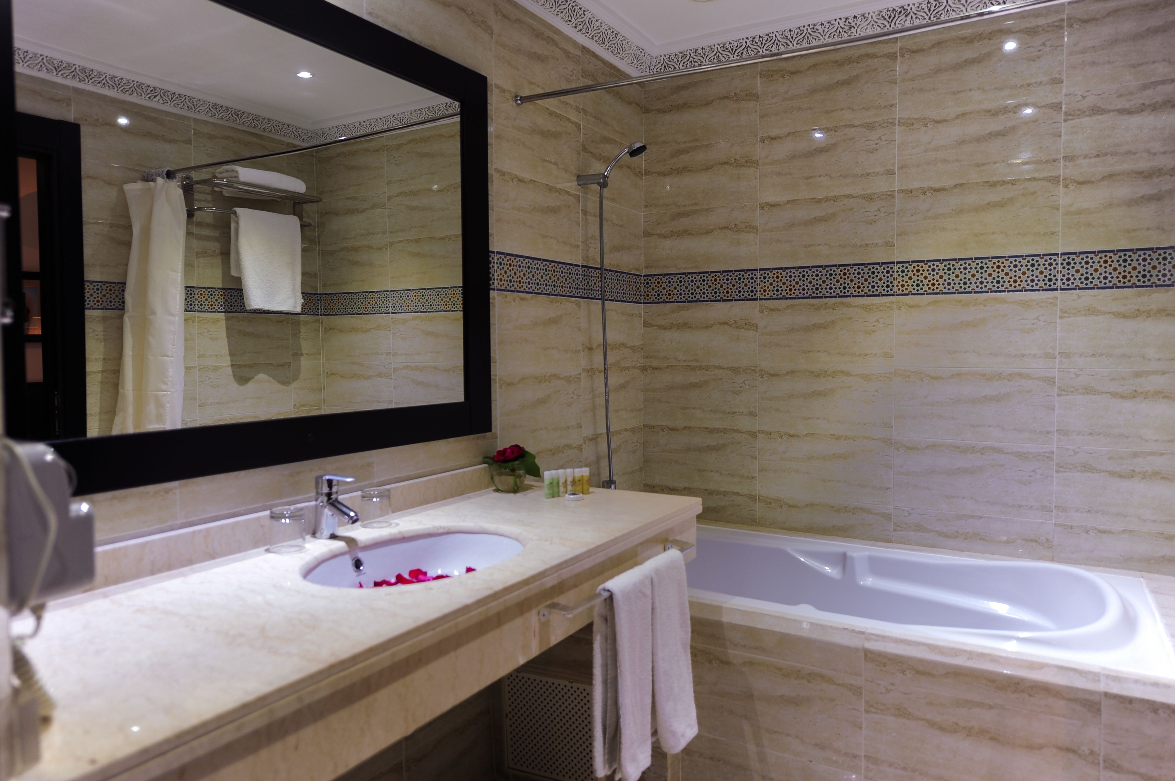 A bathroom with a sink, mirror, shower, and bathtub.