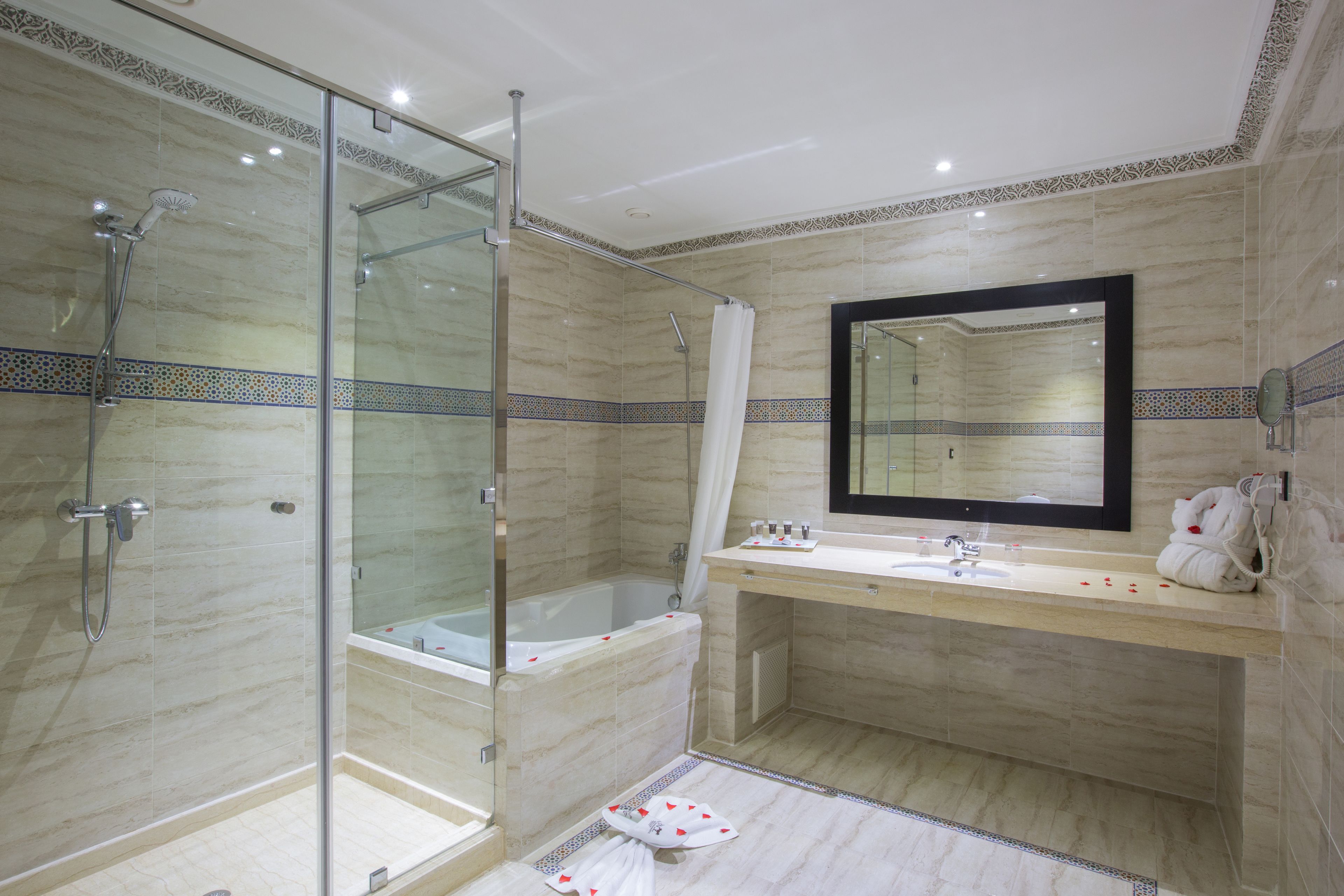 A modern bathroom with a glass-enclosed shower, a bathtub, and a vanity with a mirror.