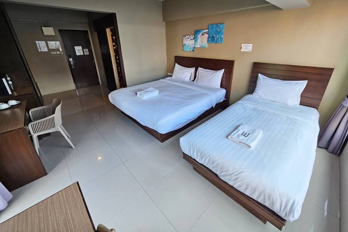 Une chambre d’hôtel avec deux lits, un bureau et une chaise.