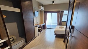 A hotel room with a bed, a desk, a TV, and a wardrobe. - Wsotel Hotel and Serviced Apartment (Songkhla)