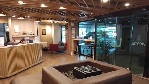A modern interior with a reception desk, seating area, and a glass wall with a view. - Wsotel Hotel and Serviced Apartment (Songkhla)