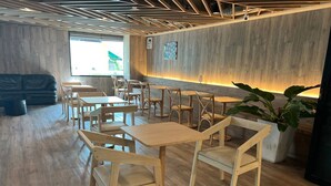 A modern cafe interior with wooden furniture, a large potted plant, and a wooden ceiling design. - Wsotel Hotel and Serviced Apartment (Songkhla)