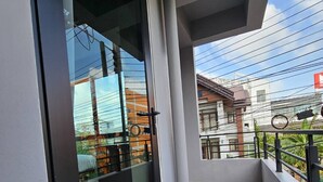 A balcony with a glass door, tiled floor, and a view of buildings and power lines. - Wsotel Hotel and Serviced Apartment (Songkhla)