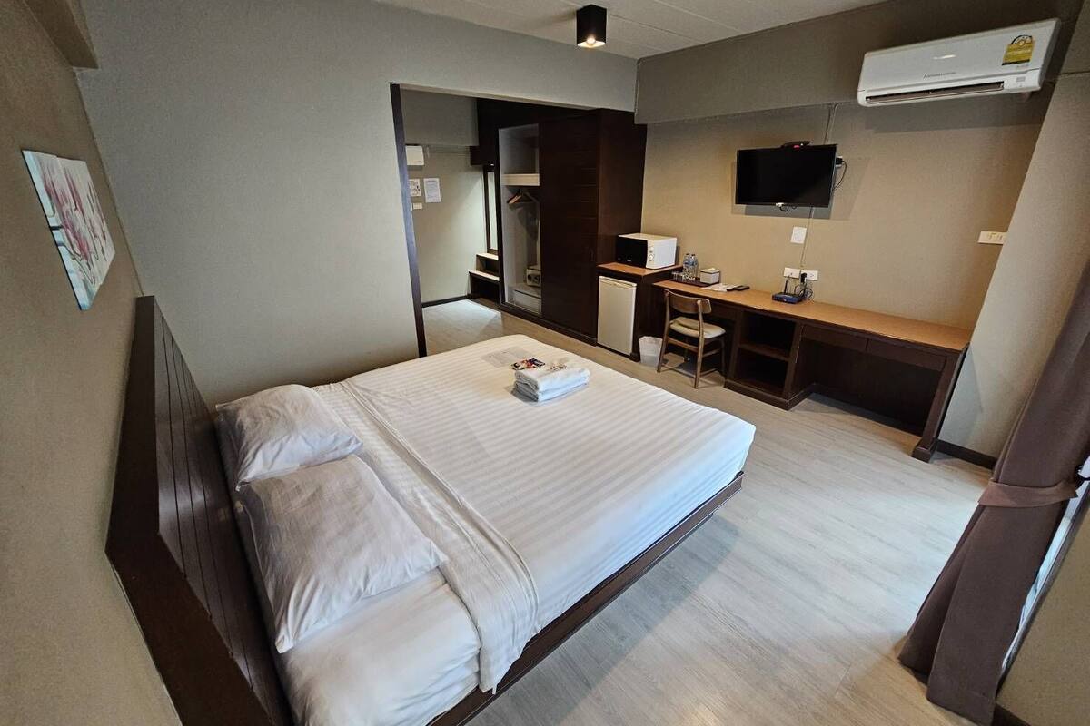 Une chambre d’hôtel équipée d’un lit, d’un bureau, d’une chaise, d’une télévision et d’un appareil de climatisation.