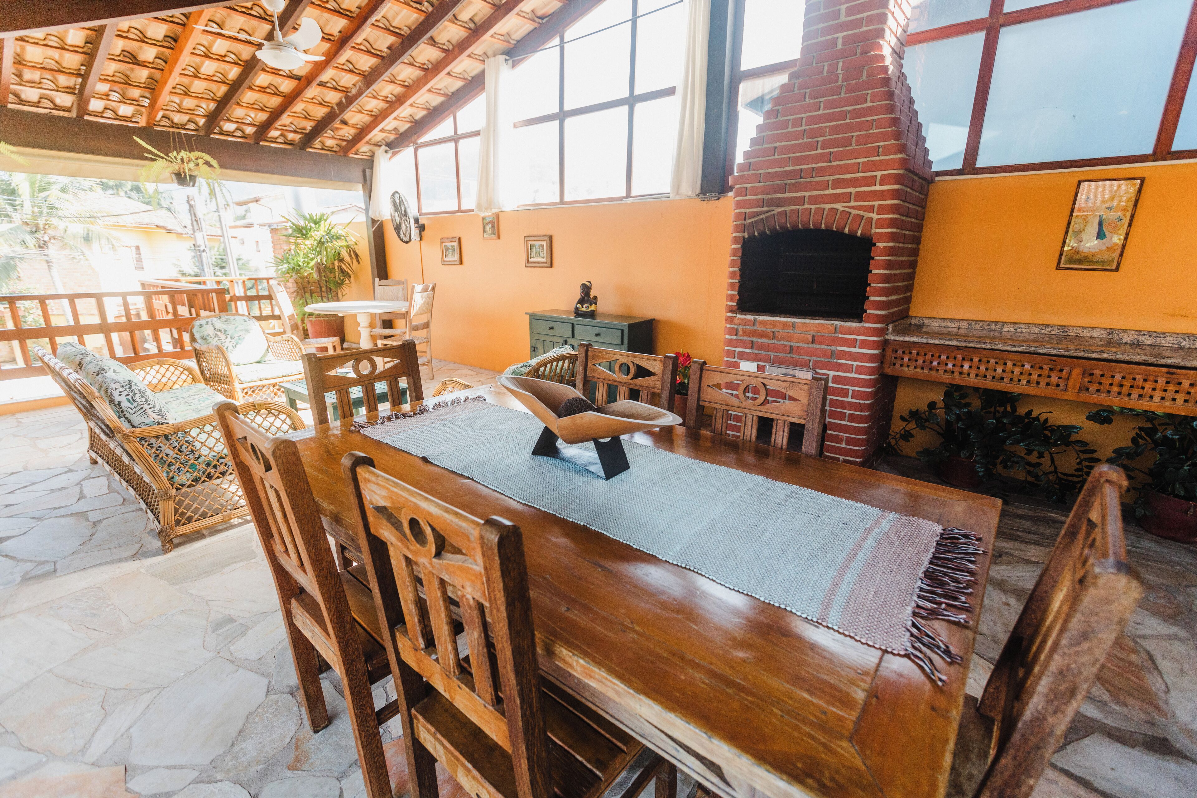 Una mesa de comedor de madera con sillas, una chimenea de ladrillo y un suelo de piedra.