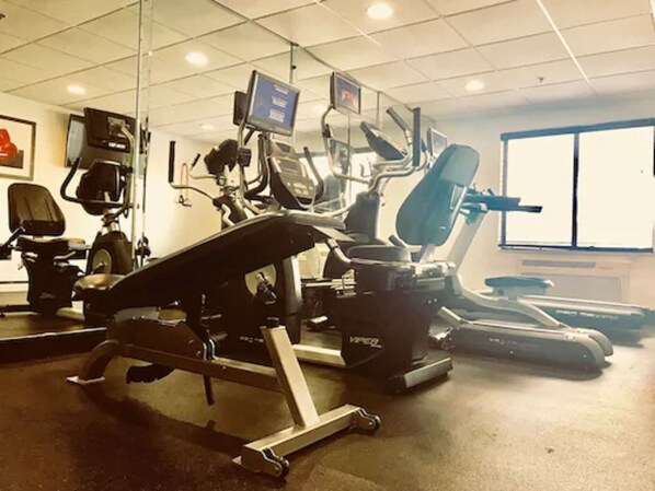 Academia com equipamentos de cardio, esteira e bicicleta ergométrica.