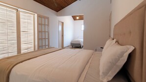 Un dormitorio con una cama grande, techo de madera y una ventana con persianas.