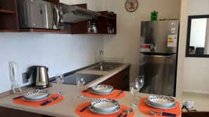 Een moderne keuken met een centraal kookeiland, klaar voor een maaltijd, voorzien van een waterkoker, wijnglazen en een magnetron.