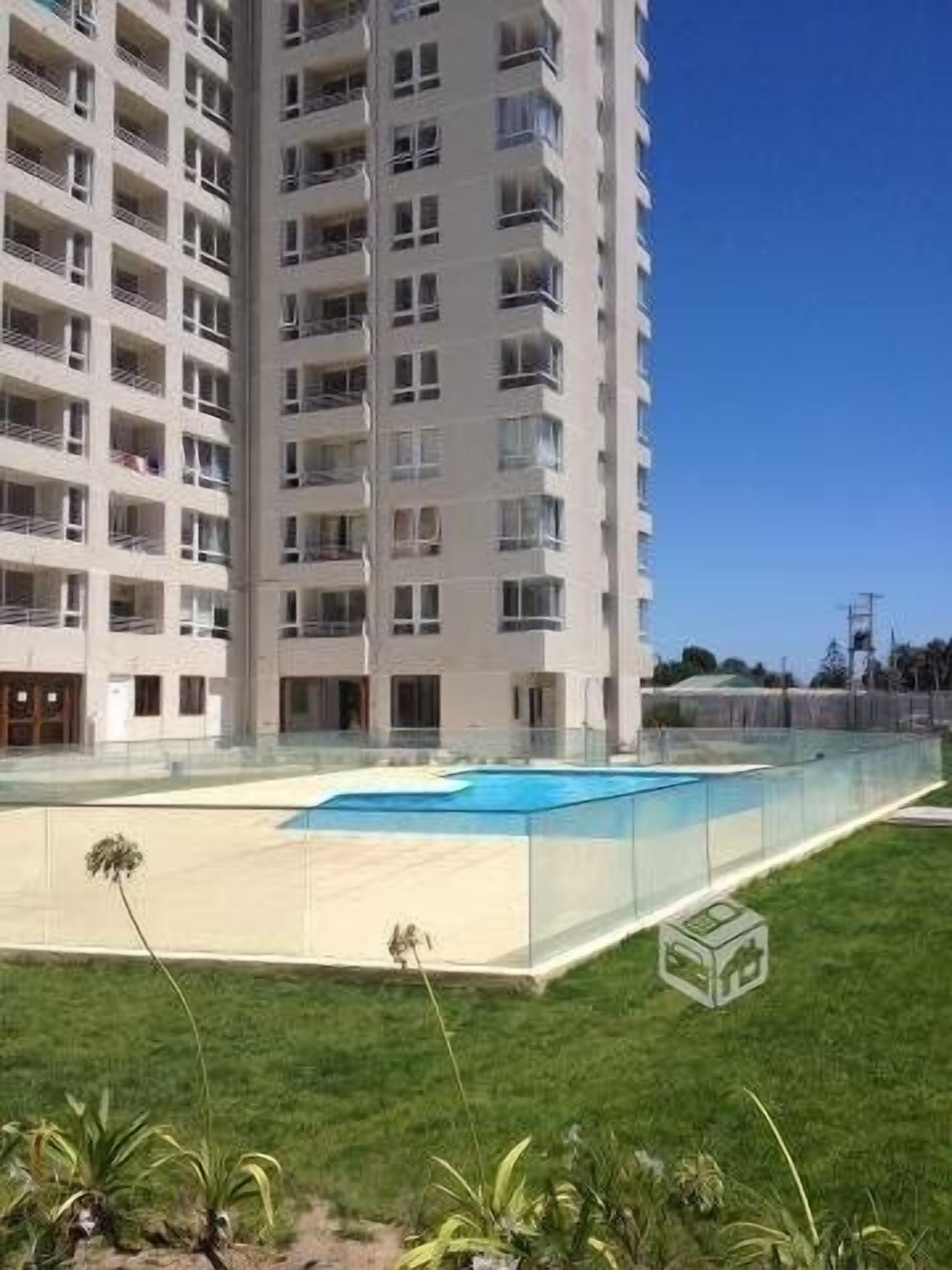 Ein modernes Apartmenthaus mit mehreren Balkonen und einem rechteckigen Schwimmbecken.