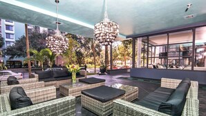An outdoor lounge area with wicker furniture, a large chandelier, and a view of the cityscape. - Avalon Hotel Downtown St. Petersburg (St. Petersburg)