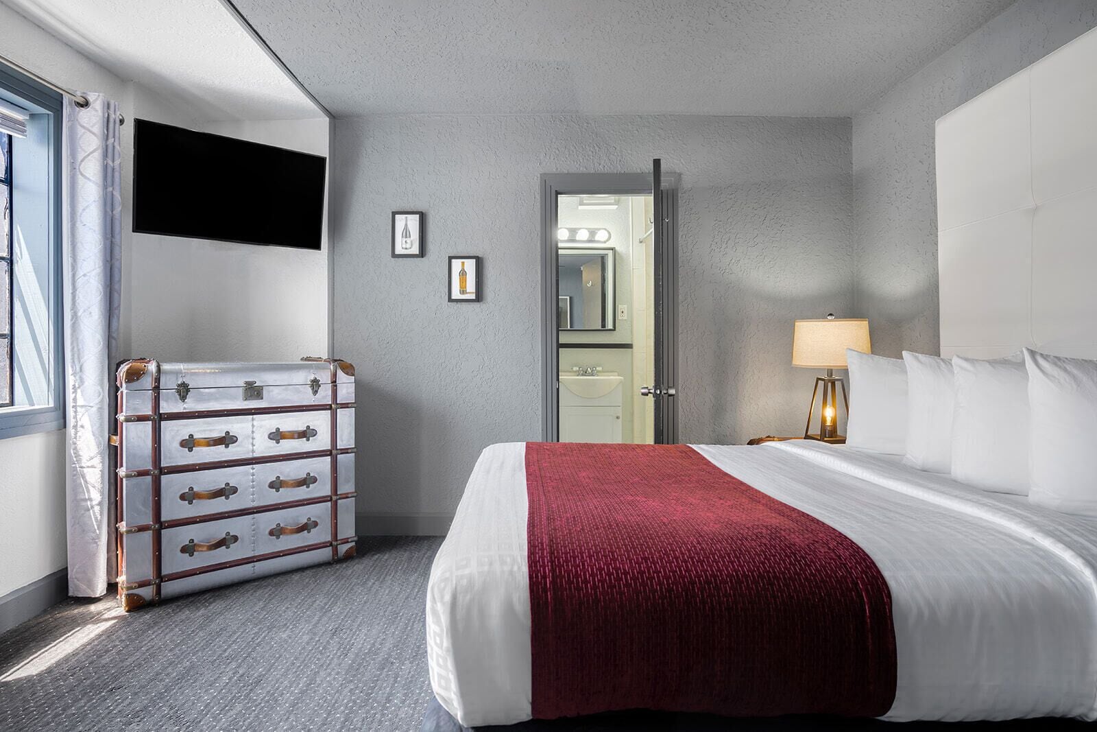Une chambre d’hôtel avec un grand lit, une commode, une coiffeuse avec un miroir et une lampe.