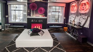 A modern living room with a fireplace labeled "AVALON," a white sofa, and a unique circular ceiling design. - Avalon Hotel Downtown St. Petersburg (St. Petersburg)