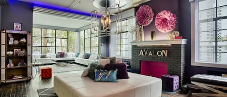 Un salon moderne doté d’une cheminée, d’une grande fenêtre et d’un plafond orné de luminaires circulaires.