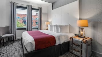 A hotel room with a large bed, two bedside lamps, a chair, and a suitcase.