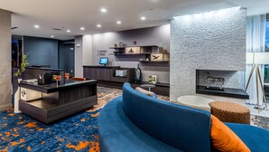 Una sala moderna con un mostrador de recepción de madera oscura, un sofá azul y una alfombra estampada.