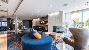 Una sala de estar moderna con un sofá azul, un sillón marrón y una mesa de centro redonda.