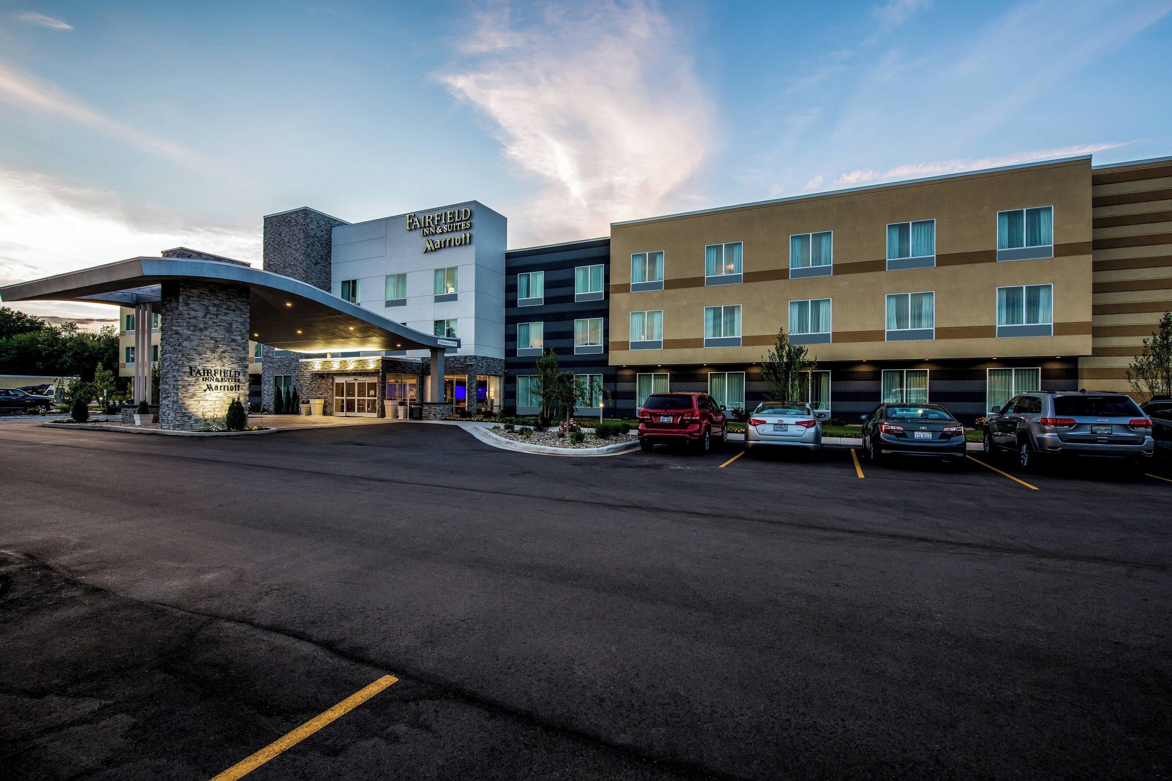Un hotel Fairfield Inn & Suites Marriott de diseño moderno, con una entrada curva y varios espacios de estacionamiento.