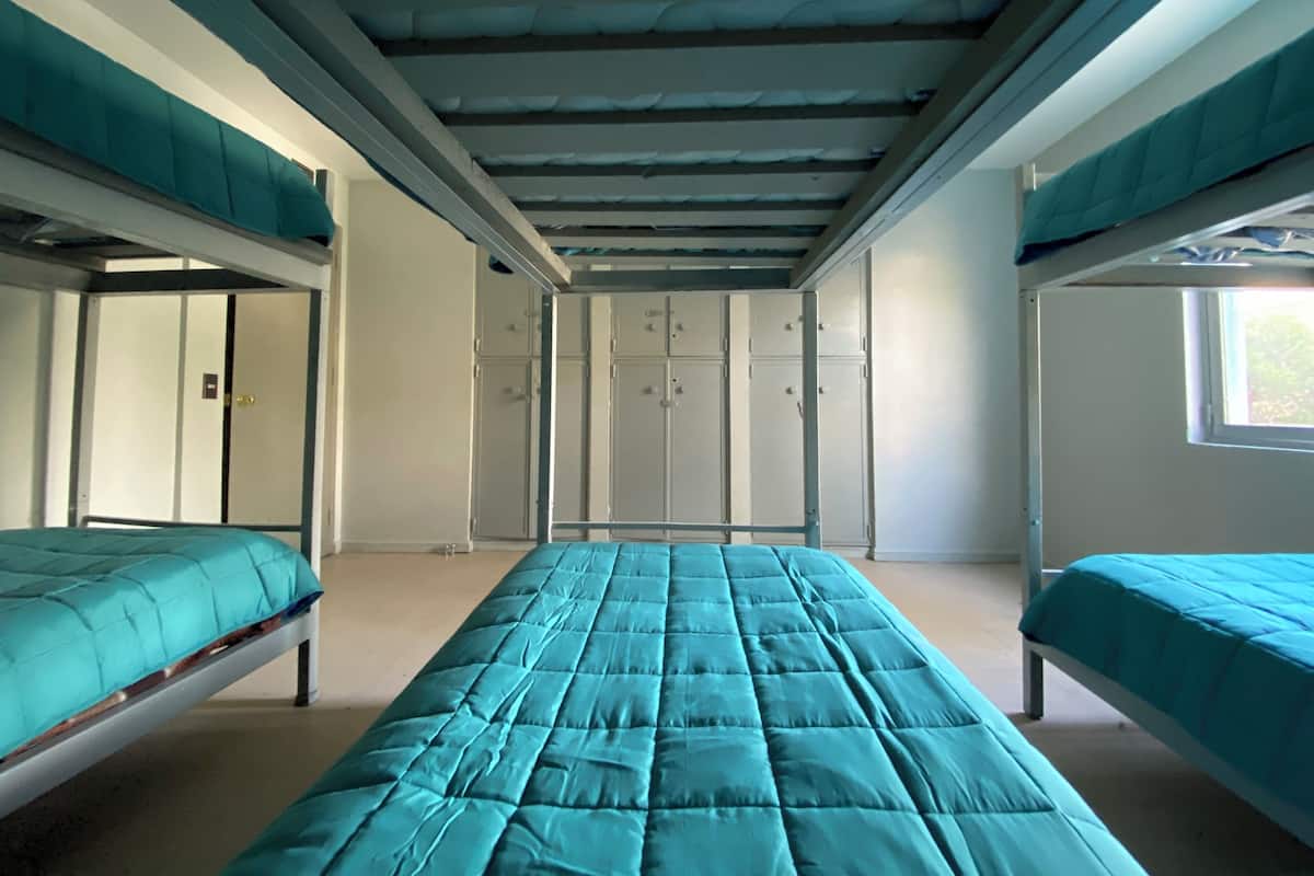 Un dormitorio con literas, una cama individual y taquillas a lo largo de la pared trasera.