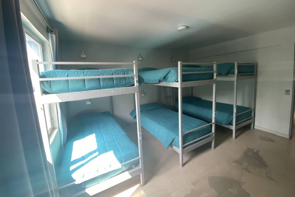 Un dormitorio tipo camarote con tres literas, cada una con colchón color turquesa y almohada a juego.