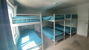 Un dormitorio tipo camarote con tres literas, cada una con colchón color turquesa y almohada a juego.