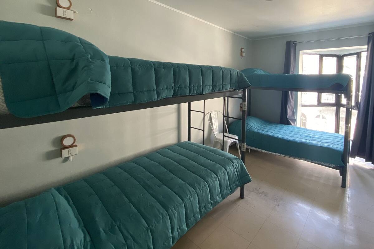 Un dormitorio con literas, una silla y una ventana con cortinas.