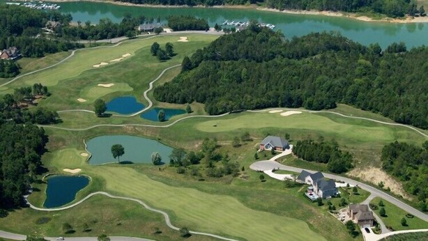 En vy över en golfbana från ovan, med flera dammar, ett klubbhus och omgivande skogsområden.