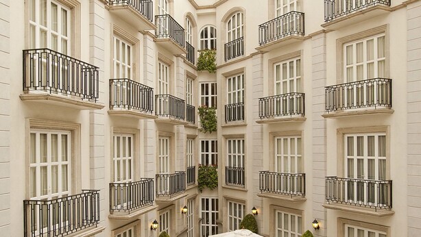 A courtyard with multiple tables and chairs, surrounded by a building with balconies and windows. - Grand Polanco Residencial (Mexico City)