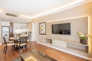 A modern living room with a dining area, a flat-screen TV mounted on the wall, and a kitchen in the background. - Grand Polanco Residencial (Mexico City)
