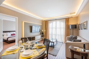 A hotel room with a dining area, a sofa, a TV mounted on the wall, and a bed. - Grand Polanco Residencial (Mexico City)