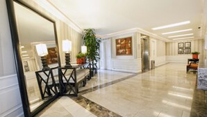 A spacious lobby with a marble floor, a large mirror, a seating area with a table and chairs, potted plants, and framed artwork on the walls. - Grand Polanco Residencial (Mexico City)