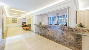 A reception area with a marble counter, a seating area with chairs, and a view of the interior through the glass door. - Grand Polanco Residencial (Mexico City)