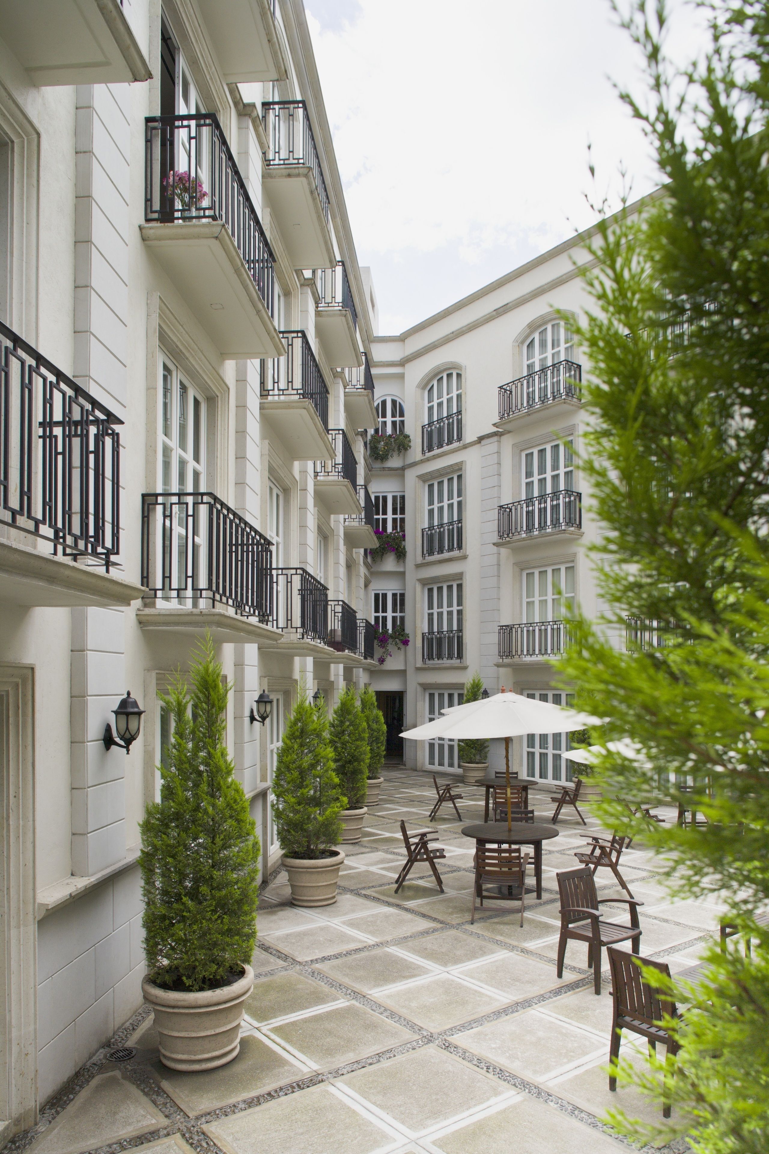 A courtyard with outdoor seating, potted plants, and a building with multiple balconies.