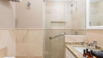 A modern bathroom with a glass-enclosed shower, a white toilet, and a granite countertop.