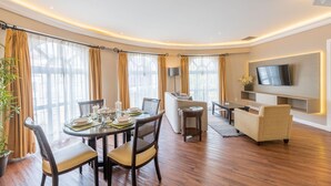 A modern living room with a dining area, a sofa, a TV mounted on the wall, and a potted plant. - Grand Polanco Residencial (Mexico City)