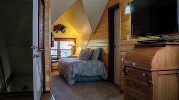 A bedroom with a bed, wooden walls, a television, and a dresser.