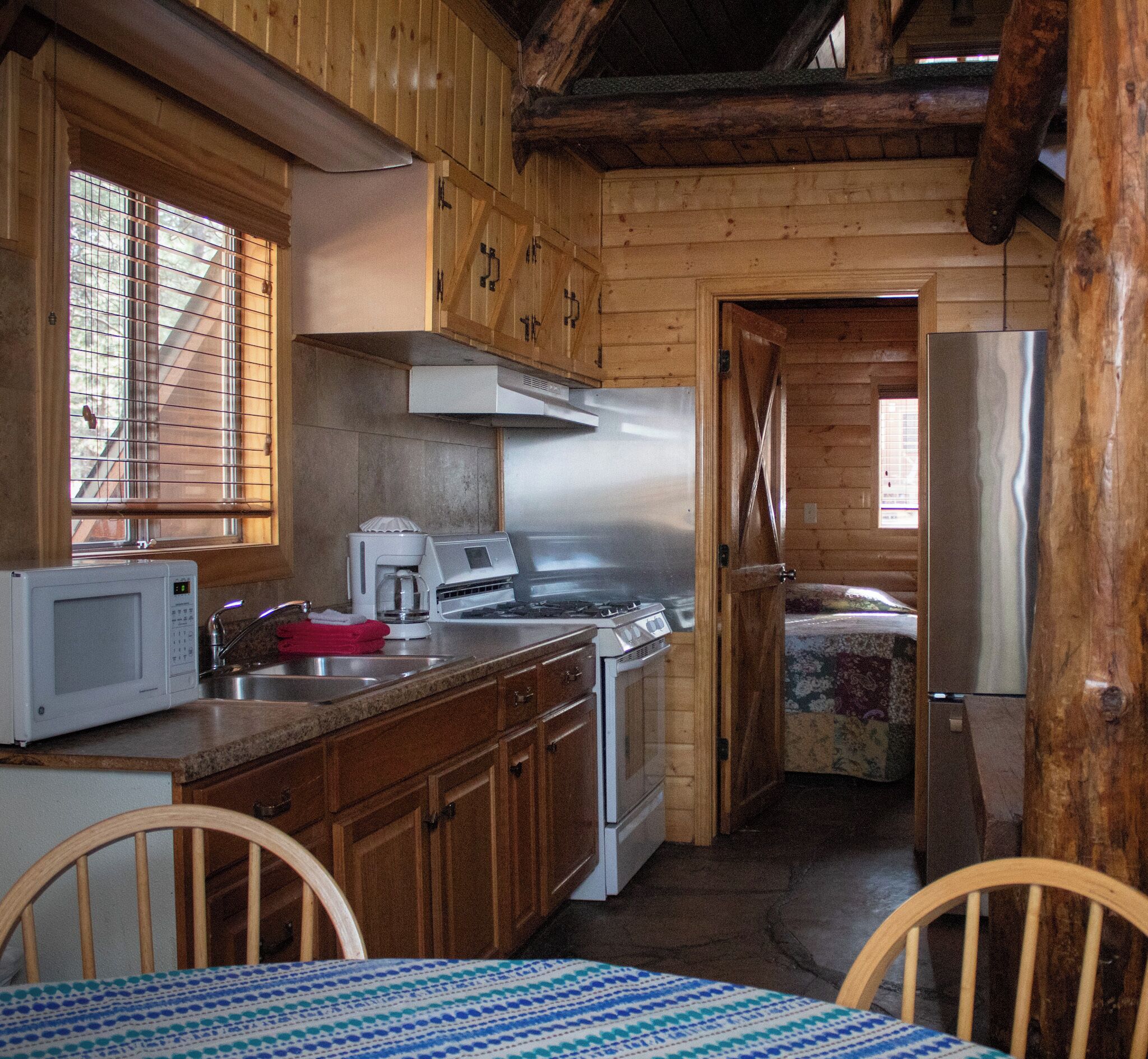 A rustic kitchen with wooden cabinets, a stainless steel stove, and a microwave.