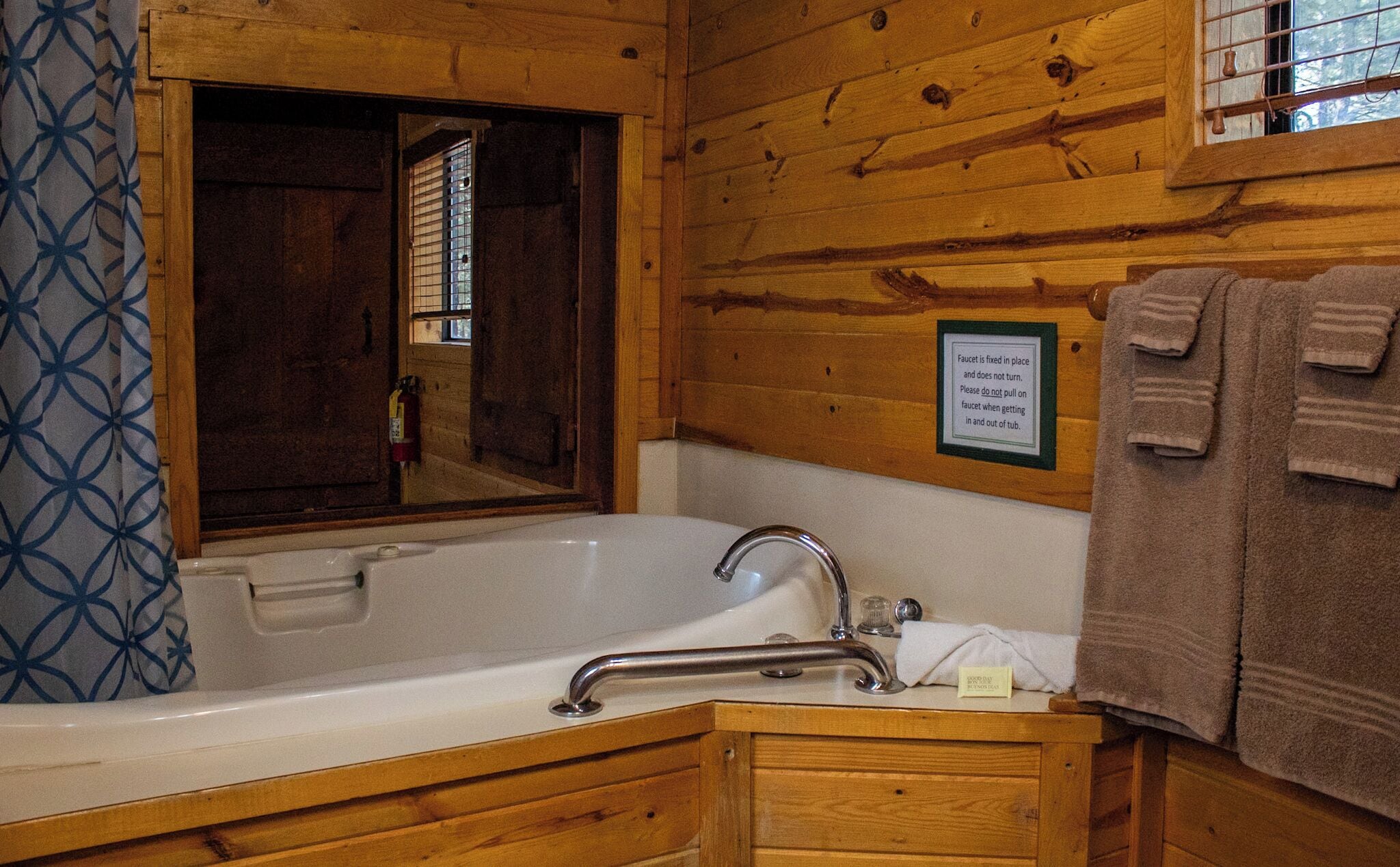 Une salle de bain rustique, avec des murs en bois, comprenant une baignoire, un miroir et un porte-serviettes.