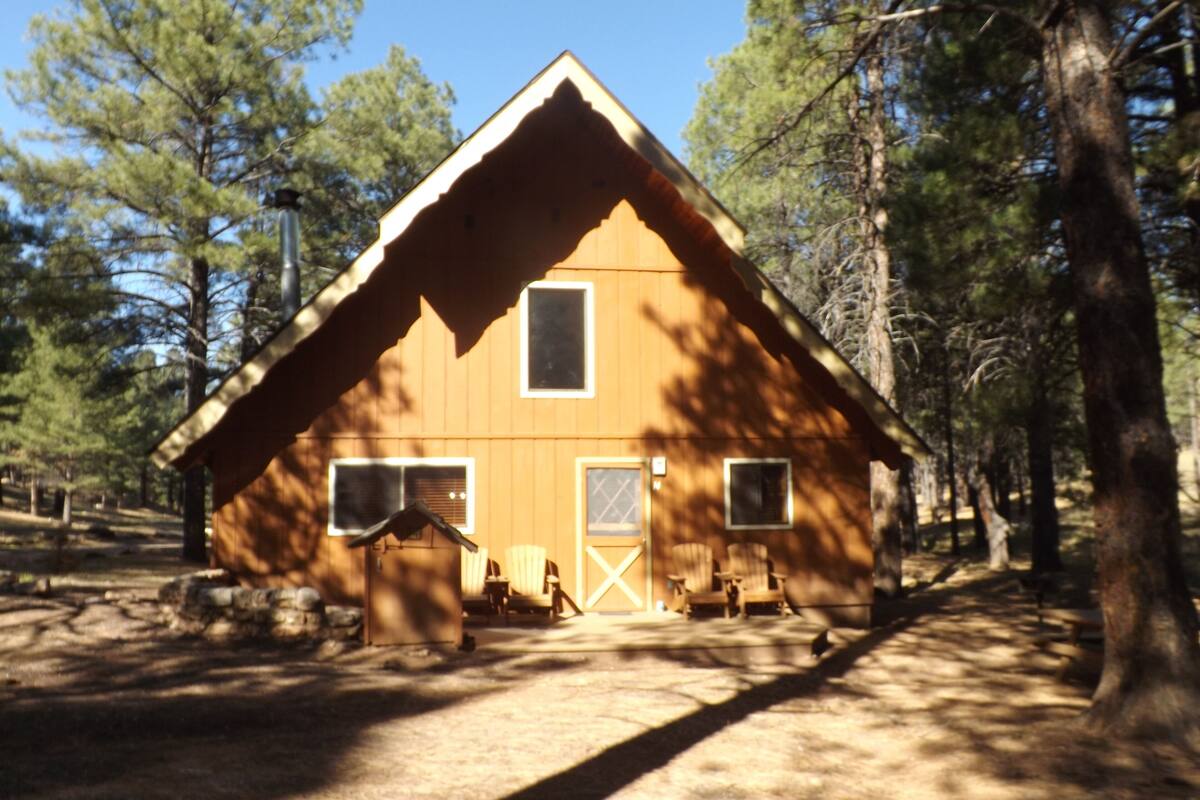 A wooden cabin with a gabled roof, a front porch, and a garage.