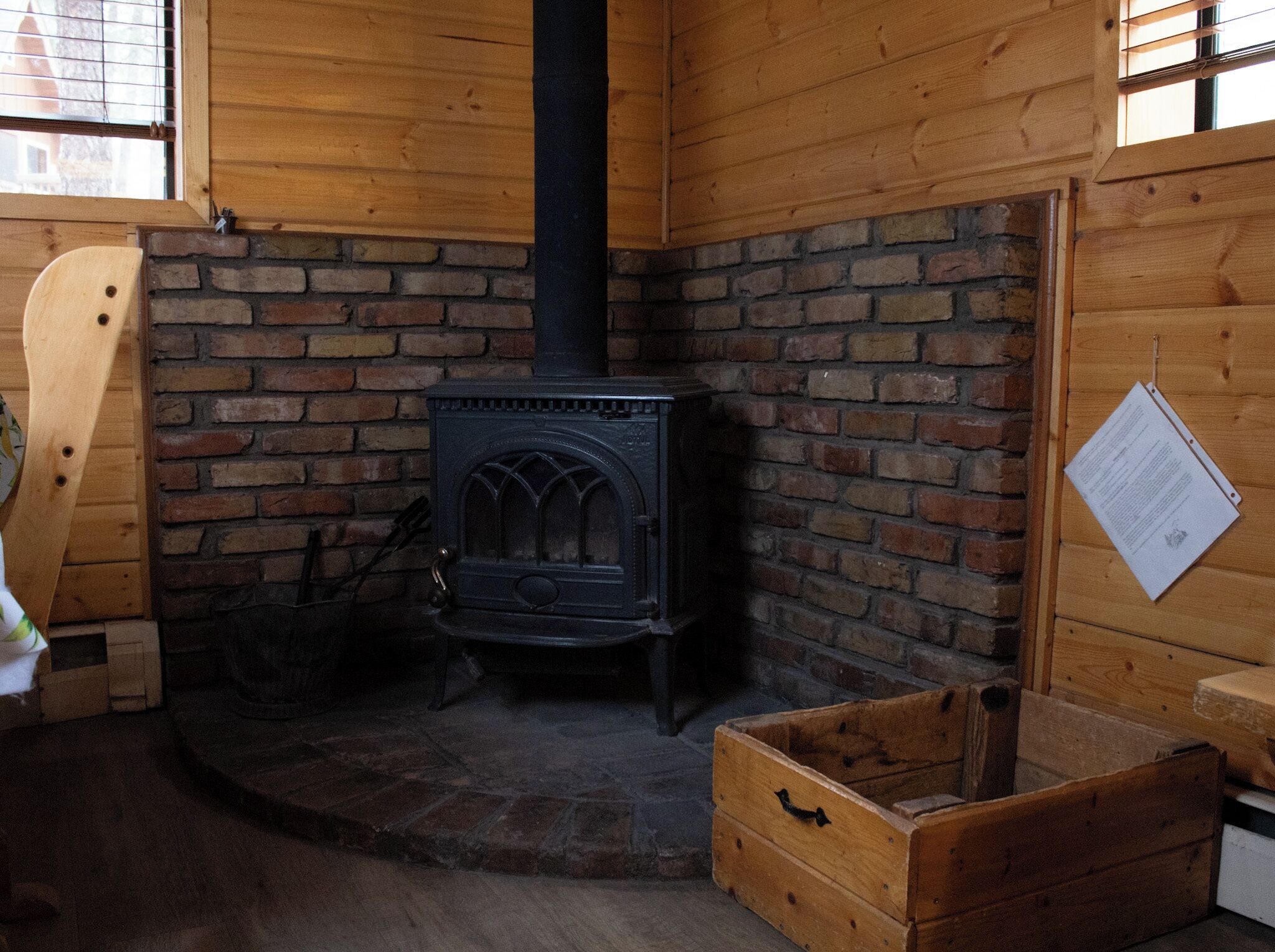 A rustic room with a brick fireplace, wooden walls, and a wooden chest.